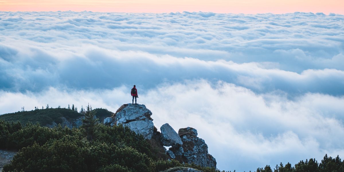 Happy hiker reaching life goal, success, freedom and happiness, achievement in mountains. Climber celebrating success on top of mountain peak in a majestic sunrise or sunset in Ceahlau Massif, Romania
